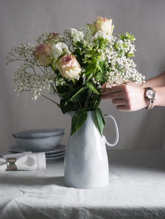 Flowers being arranged for a romantic meal for two in a Malmo jug
