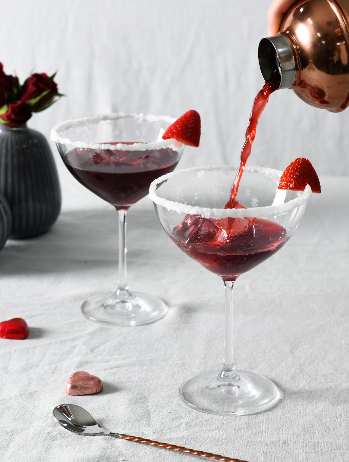 Pouring Valentine's Love Potion cocktail from a ProCook cocktail shaker into champagne coupes